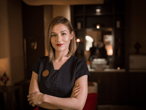 female-wellness-spa-staff-member-in-black tshirt-standing-cross-armed-in-dark-wellness-space