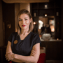 female-wellness-spa-staff-member-in-black tshirt-standing-cross-armed-in-dark-wellness-space