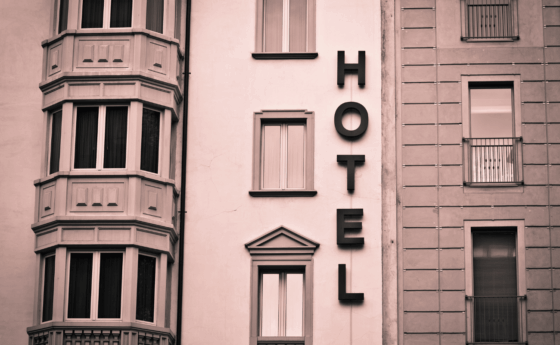 An art deco hotel facade with windows and the word hotel vertically on the building