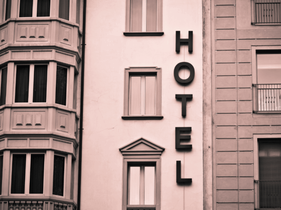 An art deco hotel facade with windows and the word hotel vertically on the building