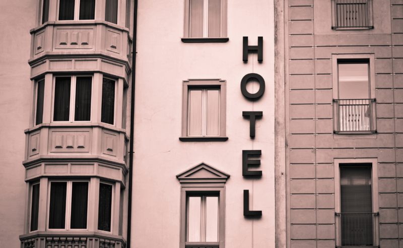 An art deco hotel facade with windows and the word hotel vertically on the building