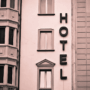 An art deco hotel facade with windows and the word hotel vertically on the building